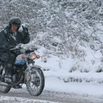 A Motorcycle rider riding his bike in heavy snowfall