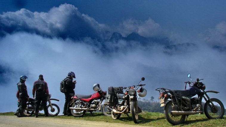 A group travel bikers is standing bsides the road to capture view from the top