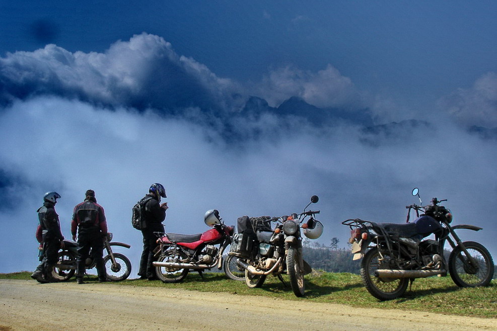 A group travel bikers is standing bsides the road to capture view from the top