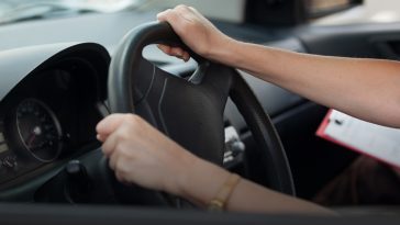 A car driver holding handle of car during licence exam