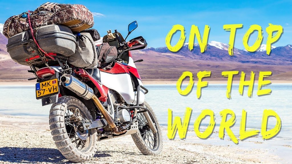 A trail Bike parked infornt of a lakes, which is located around the mountains