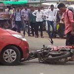A motorcycle is being hit by a car hit the motorbike bike on the road