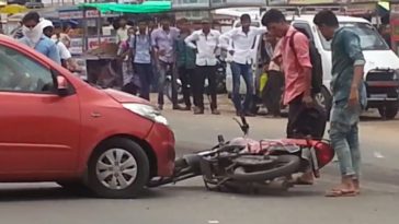 A motorcycle is being hit by a car hit the motorbike bike on the road